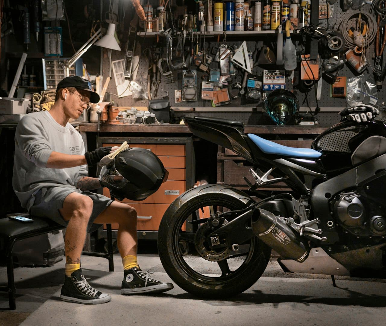 Motard nettoyant son casque à côté de sa moto